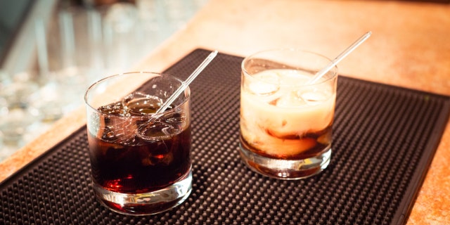 Black russian and white russian cocktails on the bar stand on rubber mat. Shallow DOF and marsala tonned