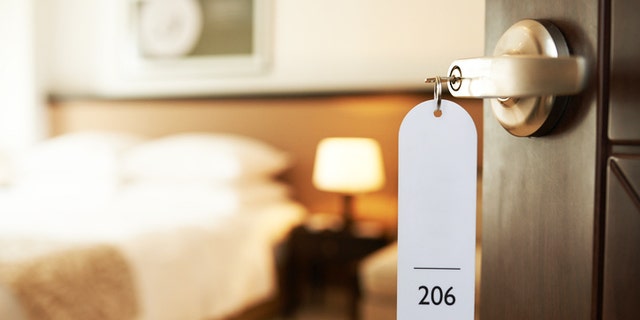 Opened door of hotel room with key in the lock