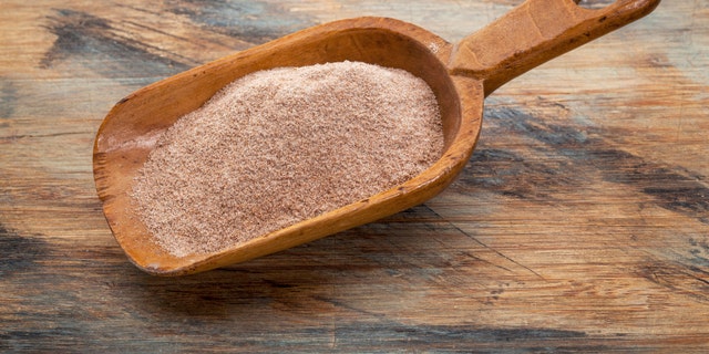 whole grain teff flour from an ancient North African cereal grass, popular in Ethiopian cuisine - a rustic scoop on wood background