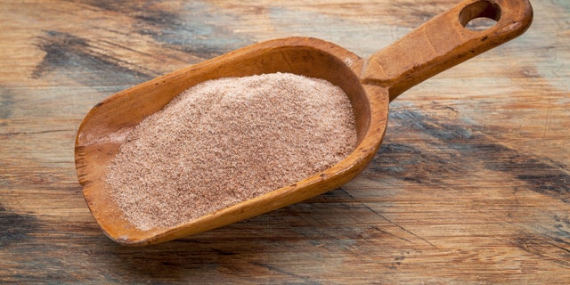 whole grain teff flour from an ancient North African cereal grass, popular in Ethiopian cuisine - a rustic scoop on wood background