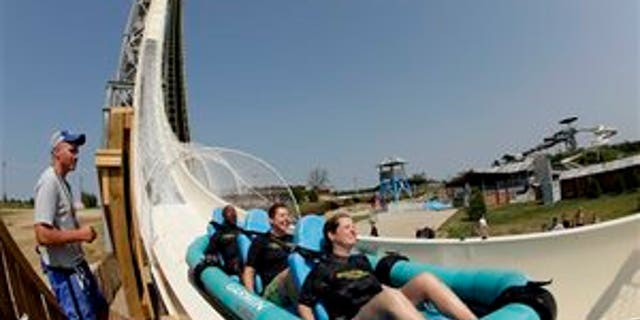 In this photo taken with a fisheye lens, riders go down the world's tallest water slide called "Verruckt" at Schlitterbahn Waterpark, Wednesday, July 9, 2014, in Kansas City, Kan. The 168-foot-tall waterslide is scheduled to open to the public Thursday, after initially being slated to open May 23. (AP Photo/Charlie Riedel)