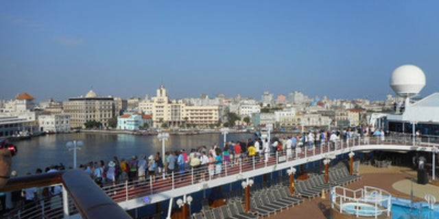 Passengers on Adonia line decks, shouting and waving to Cuban greeters on shore.
