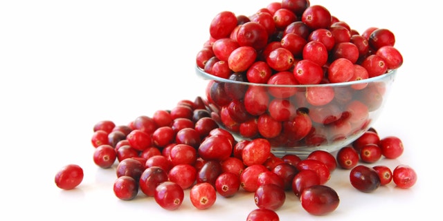 Fresh red cranberries in a glass bowl on white background