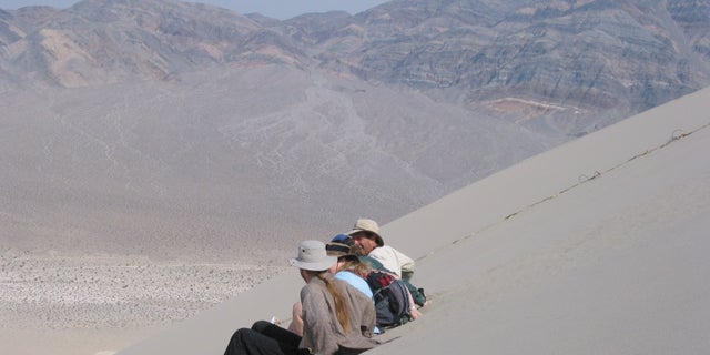 Creating a boom by sliding in unison down the face of a sand dune on the 200 m high Eureka Dune in Death Valley National Park, California.