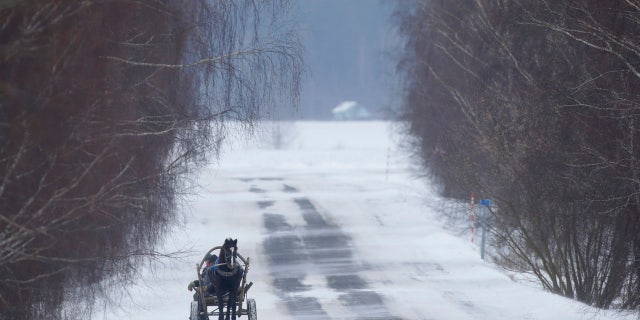 People ride on traditional cart through the snow and wind in the village of Podberezhie, 31 miles southeast of Minsk, Belarus, Wednesday, Feb. 28, 2018.