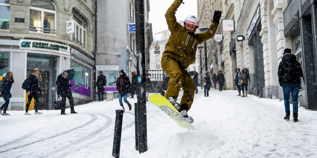 Sylvain rides his snowboard on a snow-covered street during a snowfall in Lausanne, Switzerland, Thursday, March 1, 2018.
