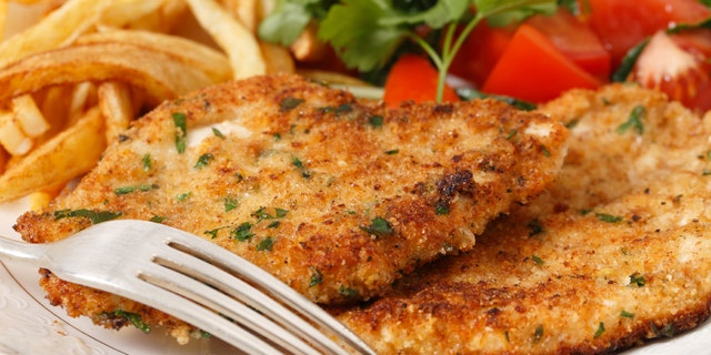 breaded homemade chicken schnitzels or escalopes with french fries and a tomato and green salad