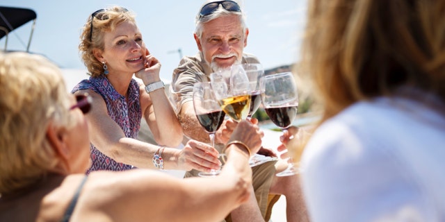 Senior friends toasting each other with wine on yacht