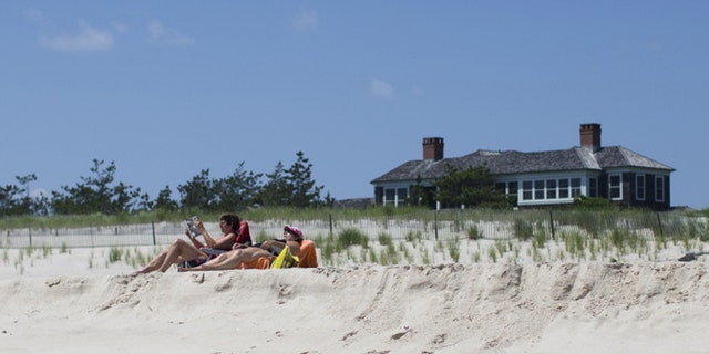 Beachgoers relax near a beachfront property in Southampton, N.Y.