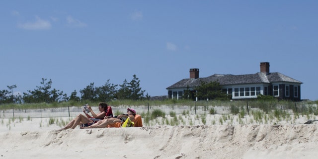 Beachgoers relax near a beachfront property in Southampton, N.Y.