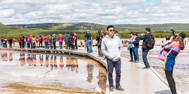 Yellowstone National Park, USA - May 17, 2016: Tourists taking pictures from boardwalk in Grand Prismatic spring in Midway Geyser Basin