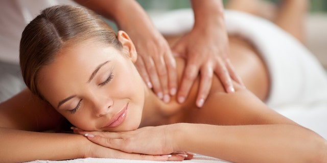 Young happy woman receiving shoulder massage at spa and beauty salon