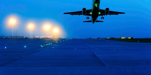 passenger plane fly up over take-off runway from airport at sunset