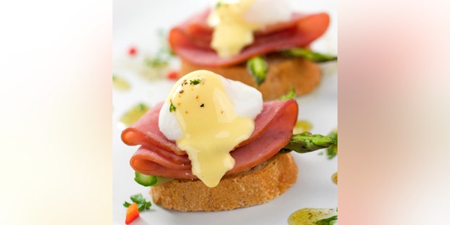 Two delicious eggs benedict with asparagus and garnish. Shallow dof.