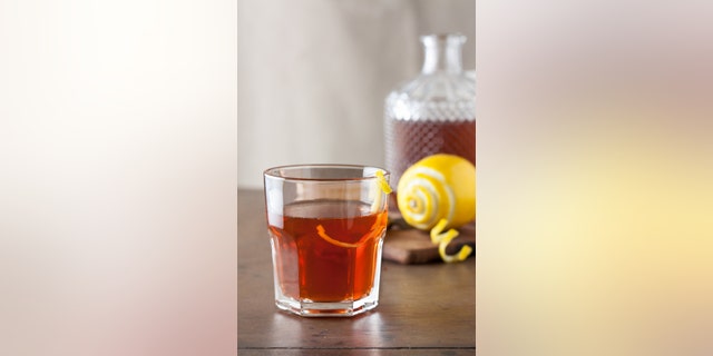 Classic sazerac cocktail with a lemon twist on wooden table