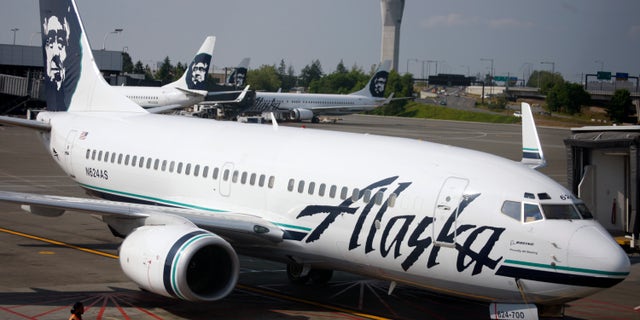 An Alaska Airlines airliner is pushed away from a gate at SeaTac Airport in SeaTac, Wash.