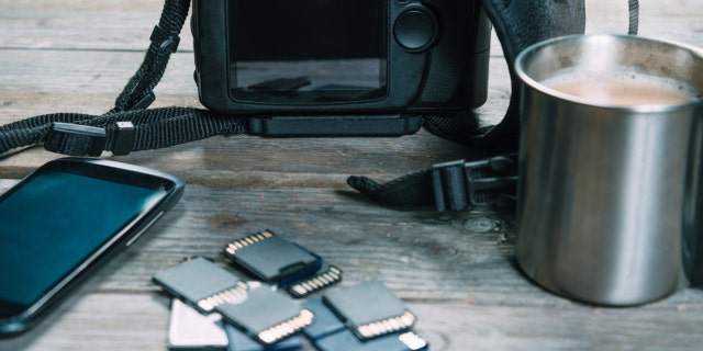 document your loved ones’s historical past and protect reminiscences 3 Digital photo camera, memory cards and mobile phone on wooden table