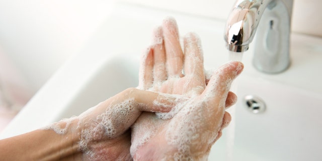 Washing of hands with soap under running water.