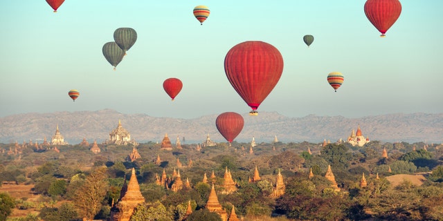 Multicolored hot air balloons over Buddhist temples at sunrise. Bagan, Myanmar.