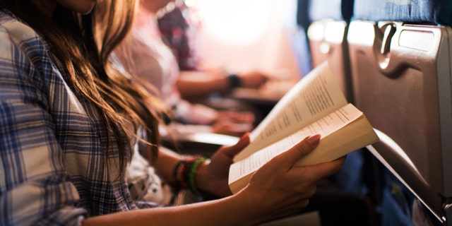 Unrecognizable woman reading a book during her flight.