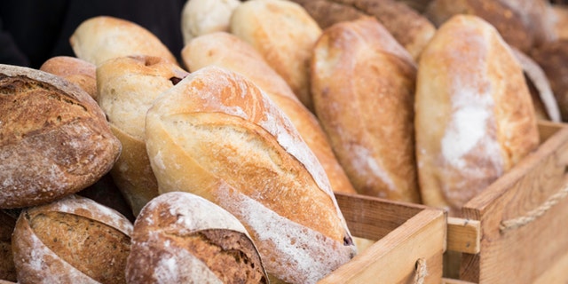 Loaves of homemade bread in wooden crates at an outdoor farmer's market.