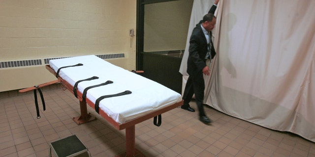 FILE – In this November 2005 file photo, Larry Greene, public information director of the Southern Ohio Correctional Facility, demonstrates how a curtain is pulled between the death chamber and witness room at the prison in Lucasville, Ohio.