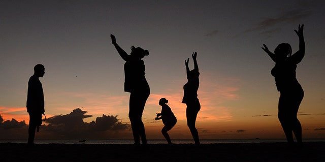 Women exercise in front of a trainer as the sun sets, March 13, 2014.