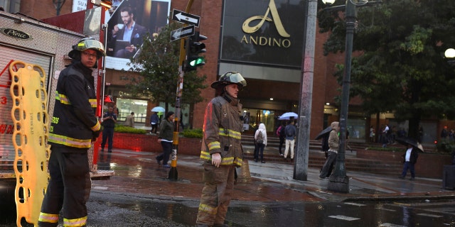 Firefighters stand outside the Centro Andino shopping center in Bogota, Colombia, Saturday, June 17, 2017.