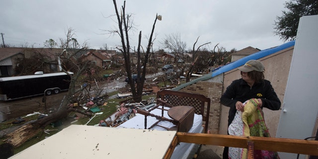Delores Downard salvages items from her son's house in Rowlett, Texas, Sunday, Dec. 27, 2015, the morning after it was struck by a tornado. At least 11 people died and dozens were injured in apparently strong tornadoes that swept through the Dallas area and caused substantial damage this weekend. (AP Photo/Rex C. Curry)
