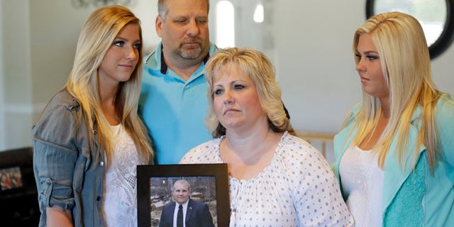 Laurie Holt holds a photograph of her son Josh while daughters Jenna, left, Katie, right, and husband Jason look on.