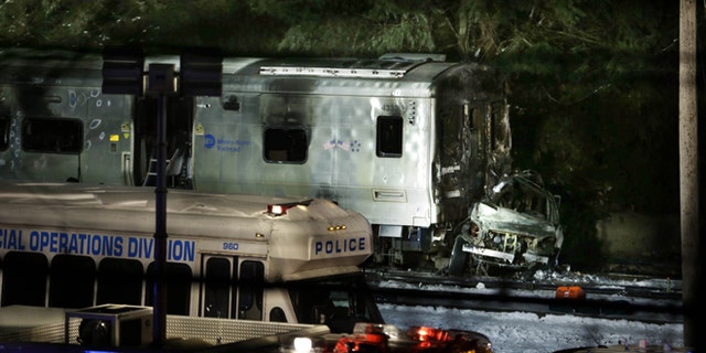 The wreckage of a car remains smashed against the front of a train in Valhalla, N.Y., Tuesday, Feb. 3, 2015. A packed commuter train slammed into a sport utility vehicle stuck on the tracks and erupted into flames Tuesday night, authorities said. (AP Photo/Seth Wenig)