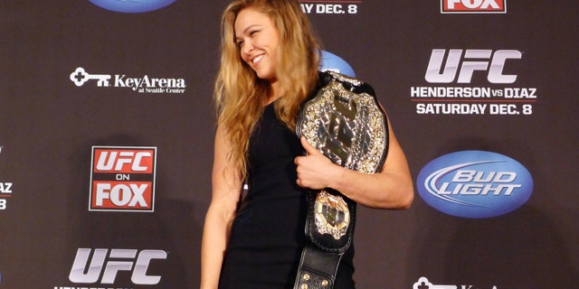 In this Dec. 6, 2012, file photo, mixed martial arts fighter Ronda Rousey shows off her UFC bantamweight championship belt presented to her by UFC president Dana White during a news conference in Seattle. (AP Photo/The Canadian Press, Neil Davidson, File)