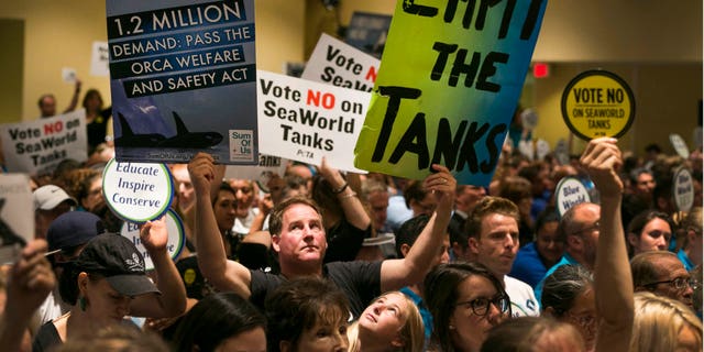 Animal rights activists hold up signs during a California Coastal Commission meeting in Long Beach, Calif.