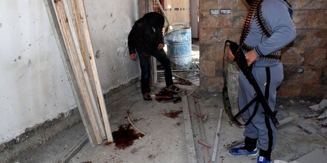 Masked anti-government gunmen inspect blood during clashes with Iraqi security forces in Fallujah, 40 miles (65 kilometers) west of Baghdad, Iraq. Wednesday, Feb. 12, 2014. The situation deteriorated significantly in late December, when security forces dismantled a protest camp near the Anbar provincial capital of Ramadi. To defuse tensions, security forces withdrew from Ramadi and the nearby city of Fallujah. Al-Qaida-linked militants promptly took over parts of Ramadi and the center of Fallujah. Since then, the government and allied tribes have been struggling to wrest control of the cities back from the militants. Al-Qaida-led militants are battling for control of mainly Sunni areas to the west of the Iraqi capital in a key test of the Shiite-led government's ability to maintain security in the country more than two years after the withdrawal of U.S. troops. (AP Photo)
