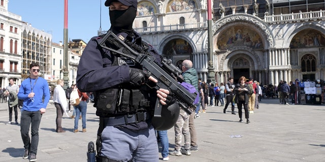 March 24: An Italian masked police officer patrols in St. Mark's square in the Venice lagoon.