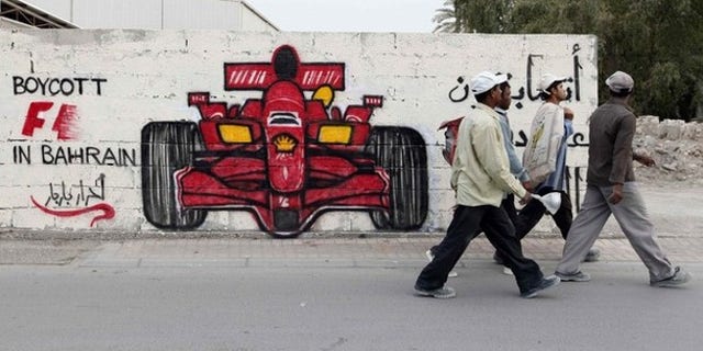 Men walk past anti-Formula One graffiti in the village of Barbar, west of Manama April 5, 2012. Former world champion Damon Hill has called on Formula 1 bosses to reconsider going ahead with this month's controversial Bahrain Grand Prix and warned that the sport's image could suffer if the race is held.