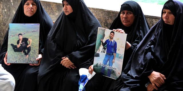 Mothers hold up posters of their sons, Iraqi soldiers who were killed, at a courtroom in Baghdad, Iraq, Wednesday, July 8, 2015. An Iraqi court has issued death sentences to 24 militants for their role in killing hundreds of soldiers last year. The slain soldiers were captured by the Islamic State group when they overran Saddam Hussein's hometown of Tikrit in summer 2014. At the time, the soldiers were trying to flee from a nearby army base. (AP Photo/ Karim Kadim