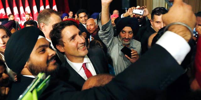 Prime Minister Justin Trudeau, center, smiles as a person takes a selfie photograph with him after he delivered remarks at the Komagata Maru Apology reception in Ottawa, on Wednesday, May 18, 2016. A New Democrat MP says Prime Minister Justin Trudeau "manhandled" another member on the floor of the House of Commons just prior to a key vote.  (Fred Chartrand/The Canadian Press via AP) MANDATORY CREDIT