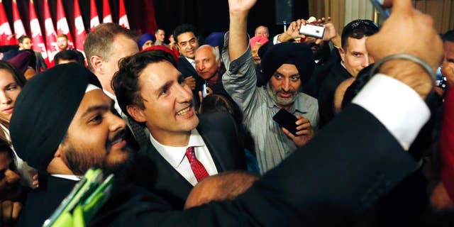 Prime Minister Justin Trudeau, center, smiles as a person takes a selfie photograph with him after he delivered remarks at the Komagata Maru Apology reception in Ottawa, on Wednesday, May 18, 2016. A New Democrat MP says Prime Minister Justin Trudeau "manhandled" another member on the floor of the House of Commons just prior to a key vote. (Fred Chartrand/The Canadian Press via AP) MANDATORY CREDIT