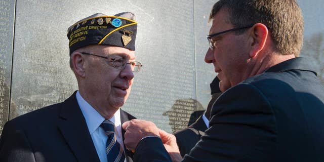Defense Secretary Ash Carter honors Vietnam Veteran Thomas Snee, who served in the Navy, with a commemorative pin to mark the 50th anniversary of the Vietnam War at the Vietnam Memorial Wall in Washington, Tuesday, March 29, 2016. (AP Photo/Molly Riley)