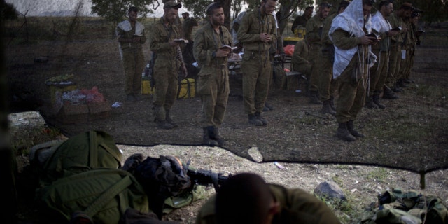 Israeli soldiers of the Golani brigade, few covered in a prayer shawls gather for the morning prayer before a military exercise in the Israeli controlled Golan Heights, near the border with Syria, Tuesday, May 7, 2013. (AP Photo/Ariel Schalit)