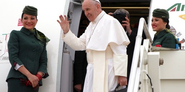Pope Francis waves as he boards a plane on his way to Cairo, Egypt, at Rome's Fiumicino inernational airport, Friday, April 28, 2017. Francis is travelling to Egypt for a two-day trip aimed at presenting a united Christian-Muslim front that repudiates violence committed in God's name. (L'Osservatore Romano/Pool Photo via AP)