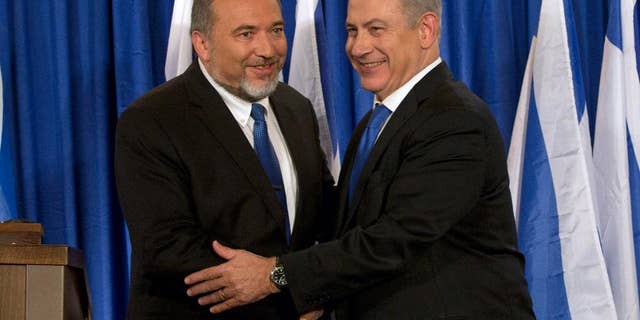 FILE - In this Oct. 25, 2012 file photo, Israeli Prime Minister Benjamin Netanyahu, right, and Foreign Minister Avigdor Lieberman shake hands in front the media after giving a statement in Jerusalem. Israel’s foreign minister says he is ending his political alliance with Prime Minister Benjamin Netanyahu. Lieberman told a news conference Monday, July 7, 2014 that he and Netanyahu have “substantial” differences. Despite the decision, Lieberman’s Yisrael Beitenu party will remain in the governing coalition, and Lieberman will remain as foreign minister. (AP Photo/Bernat Armangue, File)