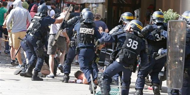French police officers charge soccer supporters during clashes in downtown Marseille, France, Saturday, June 11, 2016. Riot police have thrown tear gas canisters at soccer fans Saturday in Marseille's Old Port in a third straight day of violence in the city. (AP Photo/Darko Bandic)