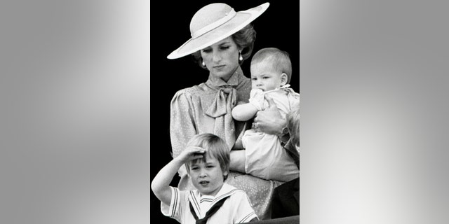 Prince William makes a royal salute as he watches the scene of Trooping the Colour from the balcony of Buckingham Palace with his brother Harry and mother Princess Diana on June 15, 1985 in London.