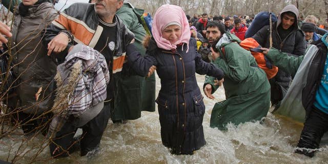 FILE - In this Monday, March 14, 2016 file photo, a woman cries as she crosses the river along with other migrants attempting to reach Macedonia on a route that would bypass the border fence, north of Idomeni, Greece. Eight asylum seekers are taking legal action against Macedonia for expelling them back to Greece after a chaotic mass border crossing earlier this year.
The migrant advocacy group ProAsyl said it helped the group file a complaint Monday, Sept. 12 with the Council of Europe's Court of Human Rights. (AP Photo/Vadim Ghirda, file)