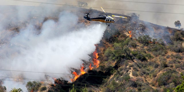 FILE - This Saturday April 20,2013 file photo shows a Los Angeles County Fire Department helicopter droping water on a fire burning on the foothills of the San Gabriel Mountains in Monrovia, Calif. Authorities say California is facing a dangerous wildfire season due to a dry winter that has left the normally green hills of spring parched and tinder-dry. (AP Photo/John Antczak,File)