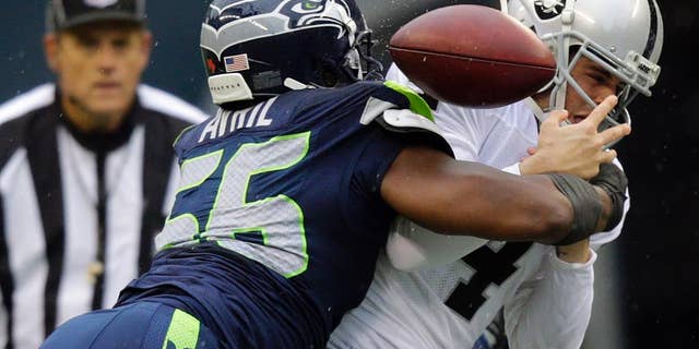 Seattle Seahawks defensive end Cliff Avril, left, causes Oakland Raiders quarterback Derek Carr to fumble in the first half of an NFL football game, Sunday, Nov. 2, 2014, in Seattle. The Raiders recovered the ball. (AP Photo/Stephen Brashear)
