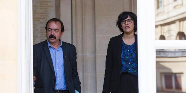The leader of France's left-wing CGT union Philippe Martinez, left, and French Labor Minister Myriam El Khomri, leave the ministry after their meeting in Paris, Friday, June 17, 2016. Martinez, the main force of opposition to an unpopular labor reform bill that has led to violence in the streets, says he's asked the labor minister to suspend parliamentary debate on the measure and re-write it. (AP Photo)