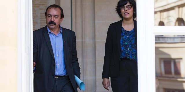 The leader of France's left-wing CGT union Philippe Martinez, left, and French Labor Minister Myriam El Khomri, leave the ministry after their meeting in Paris, Friday, June 17, 2016. Martinez, the main force of opposition to an unpopular labor reform bill that has led to violence in the streets, says he's asked the labor minister to suspend parliamentary debate on the measure and re-write it. (AP Photo)